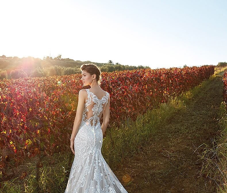 Braut in spitzenbesetztem Brautkleid im Sonnenuntergang