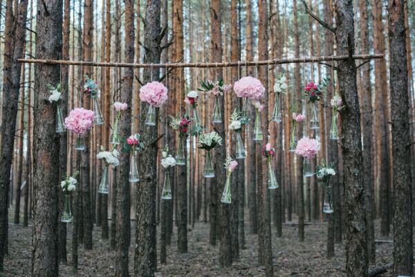 Blumen in kleinen Glasfläschchen an einem Ast hängend